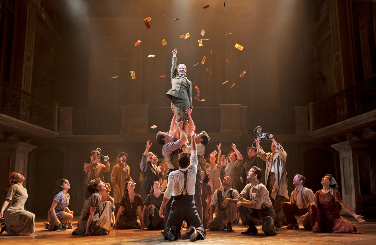 The cast of Evita lifts Eva Perón into the air as money rains down on stage, Broadway 2012